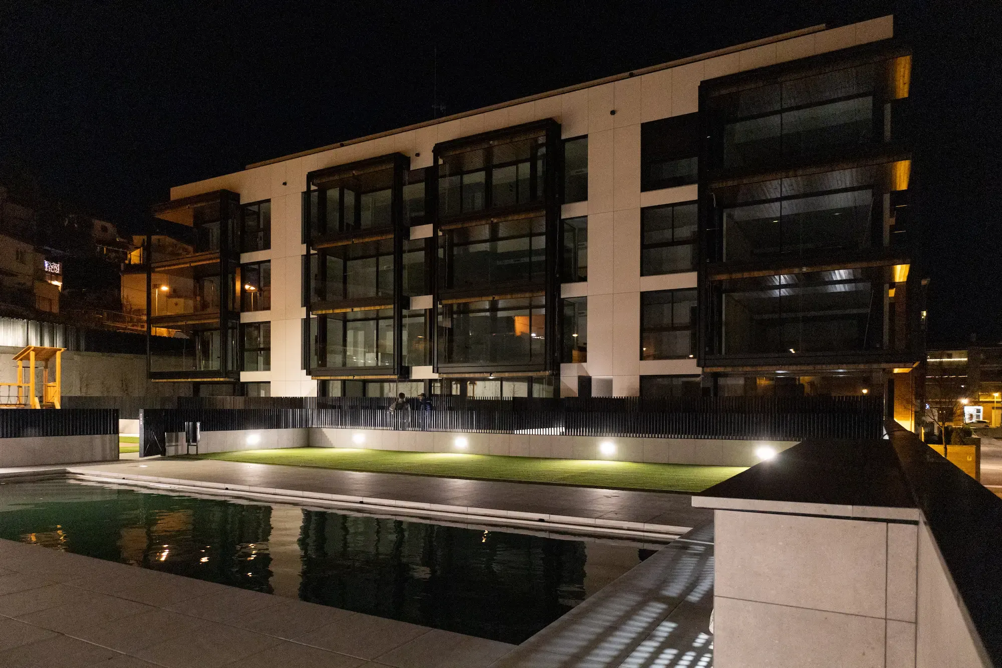 Piscina comunitaria de una promoción de Edificaciones Moreno, iluminada de noche